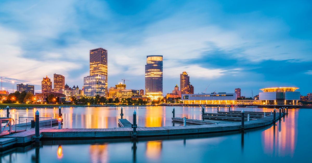 Boat dock at dusk with a city skyline across the water
